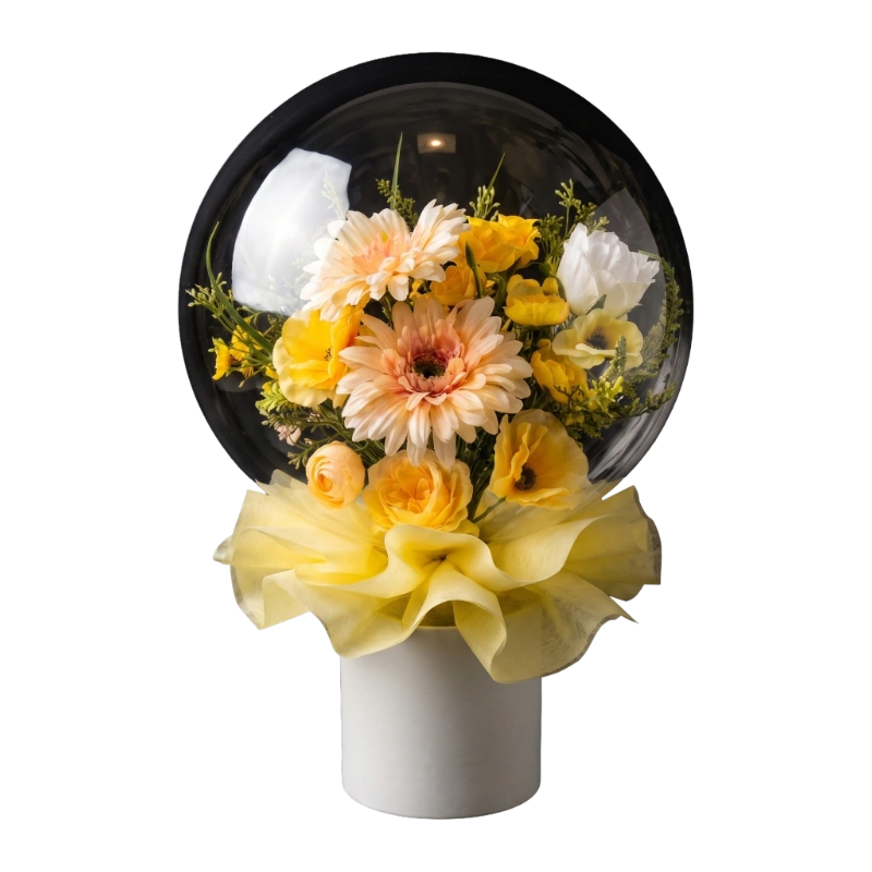 Sunlit Bloom balloon flower box with yellow, peach and white flowers displayed inside a clear bubble balloon on a white gift box.
