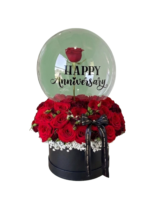 The Forever Anniversary Rose Balloon Box featuring premium red roses, baby's breath, a suspended red rose inside a transparent bubble balloon with Happy Anniversary text, presented in a luxury black hat box by Gifts & Co.