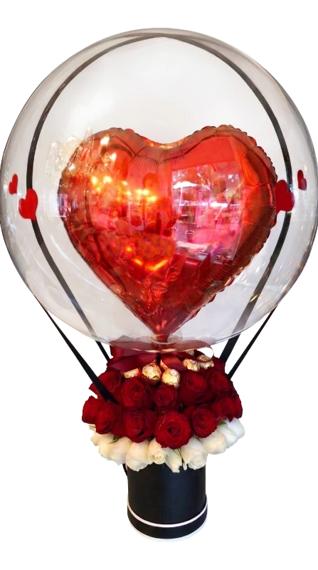 The Crimson Heart Luxe Balloon Rose Box featuring premium red and white roses, Ferrero Rocher chocolates, and a metallic heart balloon inside a crystal-clear bubble balloon presented in a luxury black hat box by Gifts & Co.
